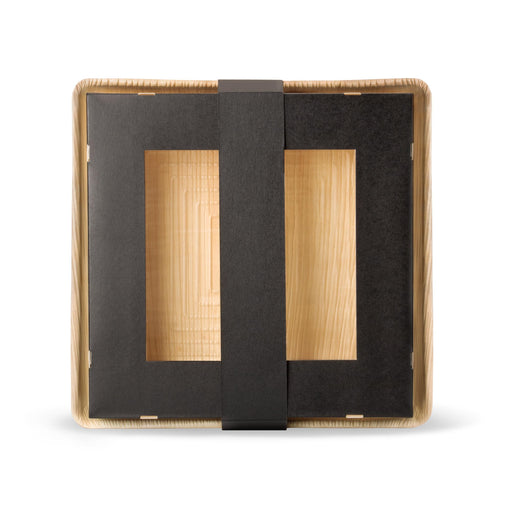 Dreiteilige, quadratische Take-Away-Box aus Kraftpapier und Palmblatt. Die hellbeige Bodenplatte dient als Basis für eine schwarze Papierbox mit Sichtfenster, die durch einen Papierring verschlossen wird.