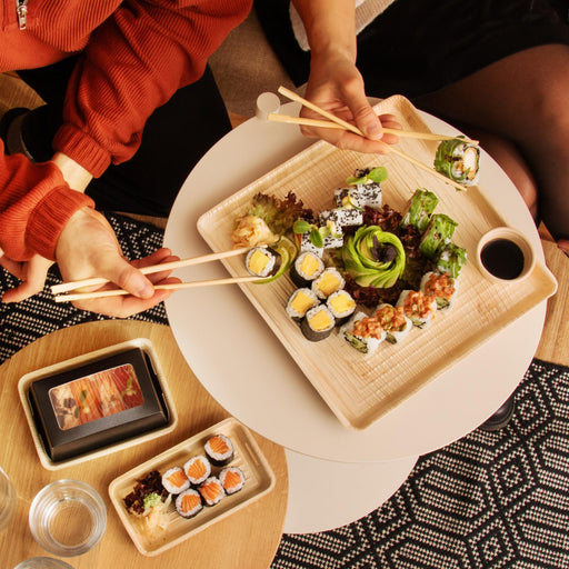 Bodenplatte der Take-Away-Box auf einem Tisch auf dem dekorativ Sushi angerichetet wurde. 